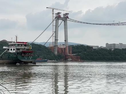 黄桷沱长江大桥是重庆在建的一座世界最大跨径公轨两用悬索桥 。以下是关于它的介绍:
• 基本概况 :黄桷沱长江大桥是渝长高速复线连接道工程的控制性工程,位于寸滩长江大桥东侧约2公里处。大桥全长1260米,主跨765米,为单跨悬吊双塔三跨连续钢桁梁悬索桥。采用双层桥面布置,上层为双向6车道城市快速路,下层中央预留双向轨道,两侧为双向4车道城市主干路及人行道。
• 建设进度:2023年3月1日,黄桷沱长江大桥开建。2024年11月26日,大桥主塔实现全部封顶 。2025年6月2日,大桥顺利完成猫道架设 。2025年7月30日,主缆架设完成,即将进入钢桁梁吊装工序 。预计将于2027年2月建成通车 。
• 设计特色 :桥梁设计以“双出门阙”为主题,主塔采用城门造型,外观大气磅礴,表达了重庆人民包容开放、热情好客的精神。
• 建设意义 :黄桷沱长江大桥建成后,将成为联系南岸弹子石片区和江北唐家沱片区的重要交通干道,进一步完善重庆快速路网建设,有效分流现渝长高速公路的交通压力,缓解沿线区域交通拥堵现状,带动区域经济发展。
