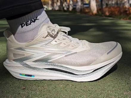 深度锐评一双跑鞋,今天聊 361 飞燃4这双鞋的基础配置,我手上这双是银白配色,看上去比较简约大气,颜值设计上还是在线的,白色可能就是不太耐脏。鞋舌比较薄, 搭配麦穗式的鞋带,后跟这个位置有两个海绵条,主要是为了防止有掉跟的现象,后跟位置没有钢港。单支 41 码克重237克,左右脚鞋子重量差距在合理的范围内,重量控制上中规中矩,鞋面是碳丝鞋面,同时也有这种比较大的透气网孔,透气强度都没问题。中底是银创尼龙弹性体,采用了peba的珠粒发泡工艺,中底比较厚,对比飞然燃4有一定加厚,但是用手按压起来,是比较软弹的感觉,中底静态脚感是一个偏软的脚感,前脚掌和后脚掌都是一个偏软弹的脚感。大底是RPU大底,防滑耐磨,足弓的位置比较宽,宽脚的跑友也能穿。中底内嵌了全掌勺型碳板,碳板前掌做了分叉,普通大众跑者也能踩得动,有着不错的滚动和助推,碳板还上翻道到了中底,主要是去提高鞋子的稳定性。#飞燃系列 #飞燃3 #碳板跑鞋 #跑鞋推荐 #跑鞋开箱