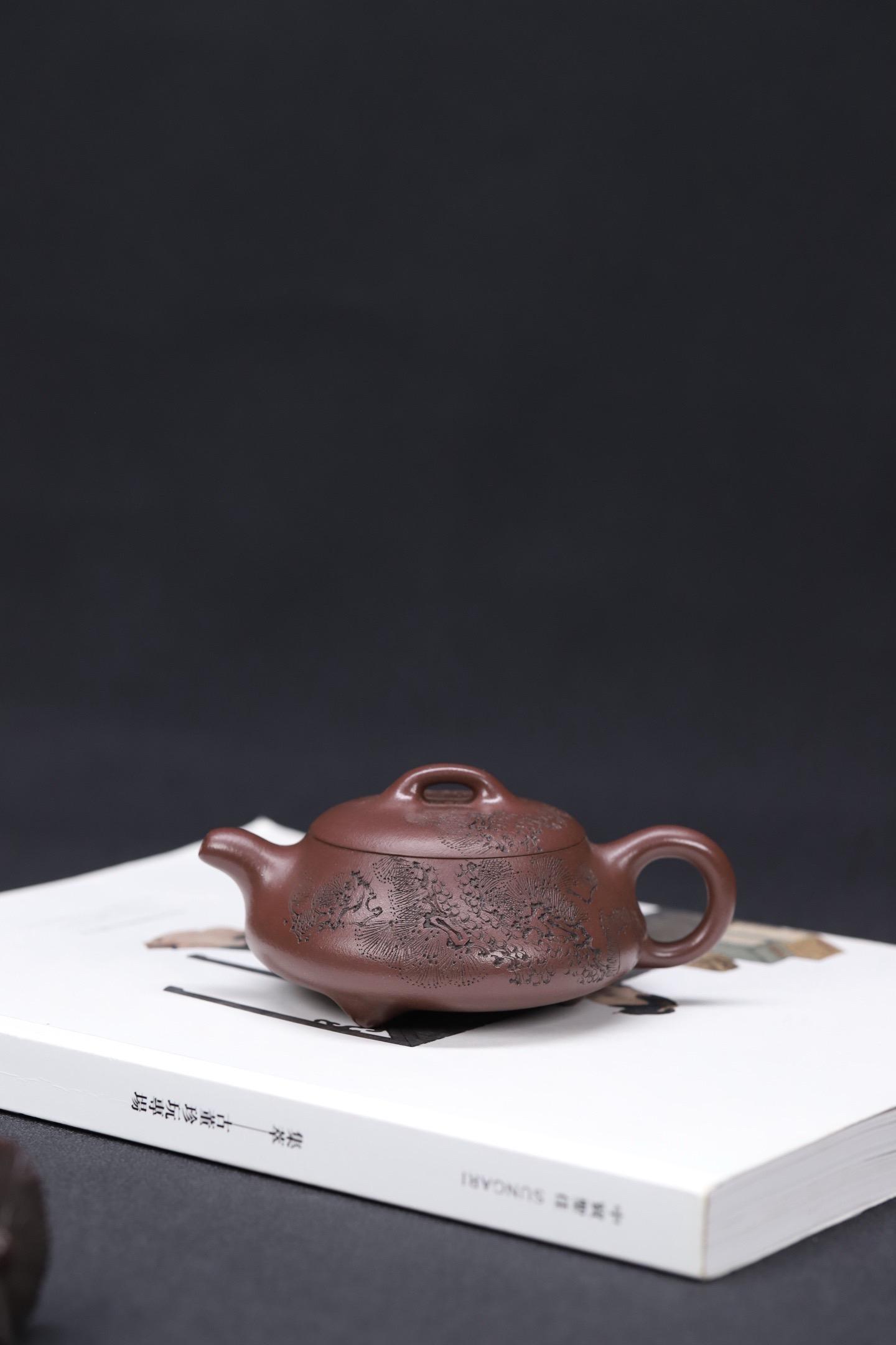 汉棠石瓢 | 精工细刻 原矿紫泥。汉棠石瓢 | 精工细刻 原矿紫泥 容量160cc 此壶壶身略显扁平,呈圆台形,宁静中彰显雍容之势,三个小尖足支撑起整个器型,平实中增添了一丝的童趣和灵气,线条规整有致,勾勒清晰美丽。