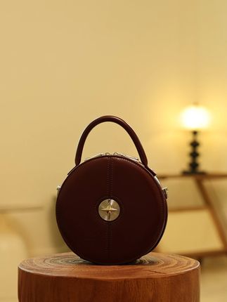 酒红圆形手提包,金属细节彰显品质 被这款酒红圆饼包的颜值拿捏了!浓郁的酒红色,复古感十足,圆形的包身可爱又独特,拿在手里很显精致。金属圆心的装饰细节满满,让包包更具设计感,质感也瞬间提升。它的容量虽不算大,但装下手机、口红等小物件完全没问题,日常通勤或逛街背上它,回头率绝对超高。#包包推荐 #包包种草 #美包分享 #小众包包 #早秋高智感职场穿搭