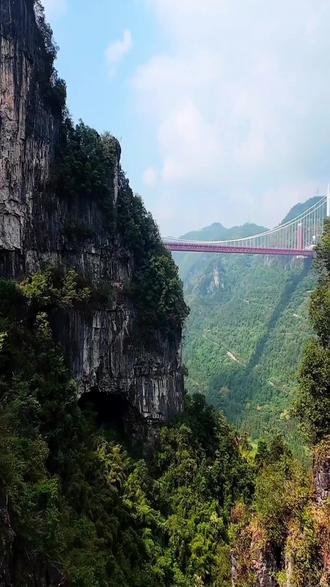 湘西矮寨大桥 #湘西矮寨大桥 是中国湖南省湘西土家族苗族自治州境内的高速通道,位于德夯大峡谷之上,是吉首市西北部公路的构成部分,也是包头—茂名高速公路(国家高速G65)关键控制性工程。矮寨大桥于2007年10月28日动工兴建,2011年8月20日完成主桥合龙工程,大桥全线贯通;于2012年3月31日通车运营。大桥西起坡头隧道,上跨德夯大峡谷,东至矮寨三号隧道;线路全长1779米,主桥全长1414米;桥面为双向四车道高速公路,设计速度80千米/小时。矮寨大桥是世界上跨度最大的跨峡谷悬索桥之一,其主跨长度为1176米,创下跨峡谷悬索桥的世界第一。此外,矮寨大桥还创造了四个世界第一,包括首次采用塔、梁完全分离的结构设计方案,首次使用“轨索滑移法”架设钢桁梁,以及首次采用岩锚吊索结构并用碳纤维作为预应力筋材。矮寨大桥不仅是一个工程奇迹,也成为了湘西自治州的一道亮丽风景线,吸引着众多游客前来参观体验。#基建狂魔 #神秘湘西 #飞行视角 #湘西