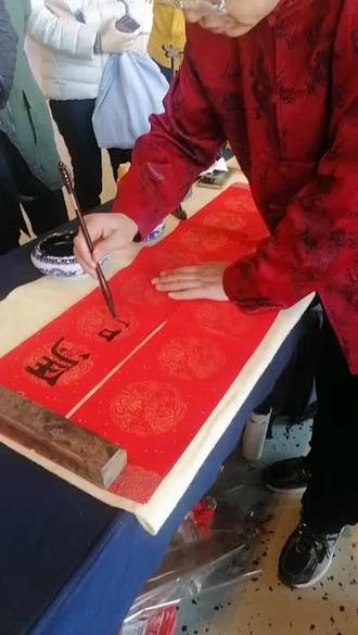 “马蹄踏雪送福至,燕语衔春入万家”。这幅对联以古朴典雅的隶书笔意,将骏马踏碎冬雪的飒爽与春燕呢喃的温情凝于纸上——左联“马蹄轻点千门雪”如飞白横扫,墨色由浓转淡似雪屑纷扬;右联“燕语频传九域春”以圆转连笔勾勒,仿佛听见剪刀尾掠过檐角的呢喃。书法家运腕生风,在红宣纸上舞出冬去春来的韵律,每一处枯润变化都是对农历马年的深情礼赞。 #手写春联更有年味 #春联书法 #传承中国书法艺术