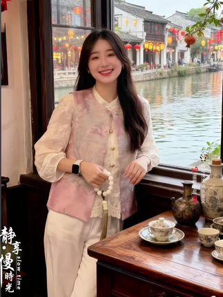 江南水乡里,新中式马夹与衬衫的国风浪漫她在江南古镇的茶馆里,邂逅了这套新中式穿搭。 浅粉色国风刺绣两面穿马夹精致典雅,一面是温婉粉调,一面是雅致黄调,搭配同系列刺绣衬衫,单穿时衬衫的盘扣与蕾丝细节尽显古典韵味,叠穿马夹则更添层次与国风气息。 她在窗边赏景,手中的白珠串与服饰相得益彰。窗外红灯笼、古民居倒映在河面上,石榴树结满红果,这般景致里,她或倚窗而立,或静品香茗,新中式穿搭在江南风情中熠熠生辉,无论是单穿衬衫的清新,还是叠穿马夹的雅致,都让她成为水乡里一抹灵动的国风风景,诉说着传统与现代融合的时尚气质~#新中式穿搭成为中秋宠儿#在时装周看见东方美 #新中式穿搭#国风新时尚 #新中式国风
