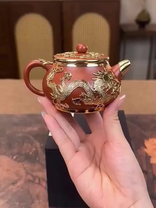 这一款是金镶玉紫砂壶,壶身镶的是双龙,采用戏珠图,采用精细镶工艺,纯手工镶嵌的,整个壶嘴、盖子、壶把手等,一体式镶嵌。 拍下还有代理盒装啊,自用送礼收藏,高端大气。非常大气啊,轻奢款啊,一百五十毫升容量,里面带球孔过滤,不管是吸水性、透气性都是极好的啊,而且是可以养包浆的,金光熠熠,贵气逼人。 这个呢,也叫精细香工艺,它也称为金香玉,非常好听的一个名字。#金镶玉紫砂壶 #高端茶器 #紫砂壶 #霸气十足 #手工壶