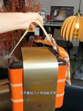这款月饼礼盒橙金配色吸睛大气,多层设计搭配手提带与丝巾,传统时尚兼备,中秋送礼、自享皆宜